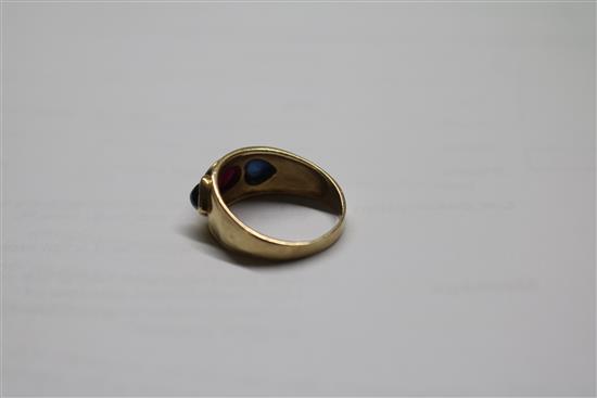 A yellow metal, cabochon ruby and sapphire three stone dress ring, size R.